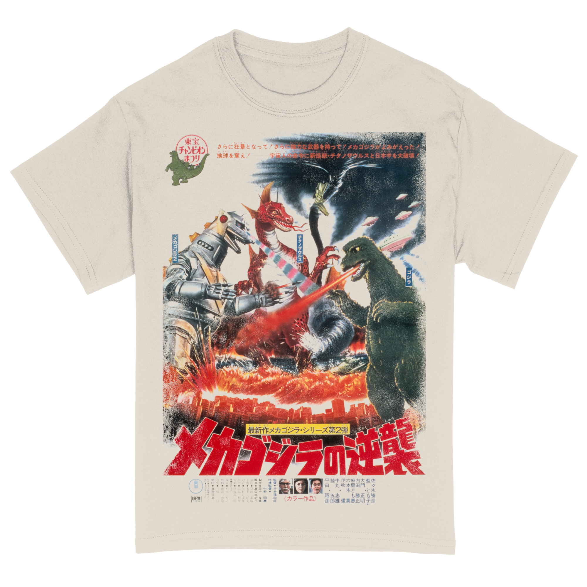 An off-white T-shirt featuring a jumbo print of a vintage Japanese movie poster from the Godzilla franchise. The graphic showcases an intense battle scene with Godzilla, Mechagodzilla, and King Caesar amid a fiery, destroyed cityscape. Japanese text is prominently displayed throughout the design, including bold red title lettering at the bottom and promotional copy at the top. Fighter jets soar through the smoky sky, and explosions surround the kaiju clash, evoking a dramatic retro cinema vibe.
