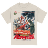 An off-white T-shirt featuring a jumbo print of a vintage Japanese movie poster from the Godzilla franchise. The graphic showcases an intense battle scene with Godzilla, Mechagodzilla, and King Caesar amid a fiery, destroyed cityscape. Japanese text is prominently displayed throughout the design, including bold red title lettering at the bottom and promotional copy at the top. Fighter jets soar through the smoky sky, and explosions surround the kaiju clash, evoking a dramatic retro cinema vibe.
